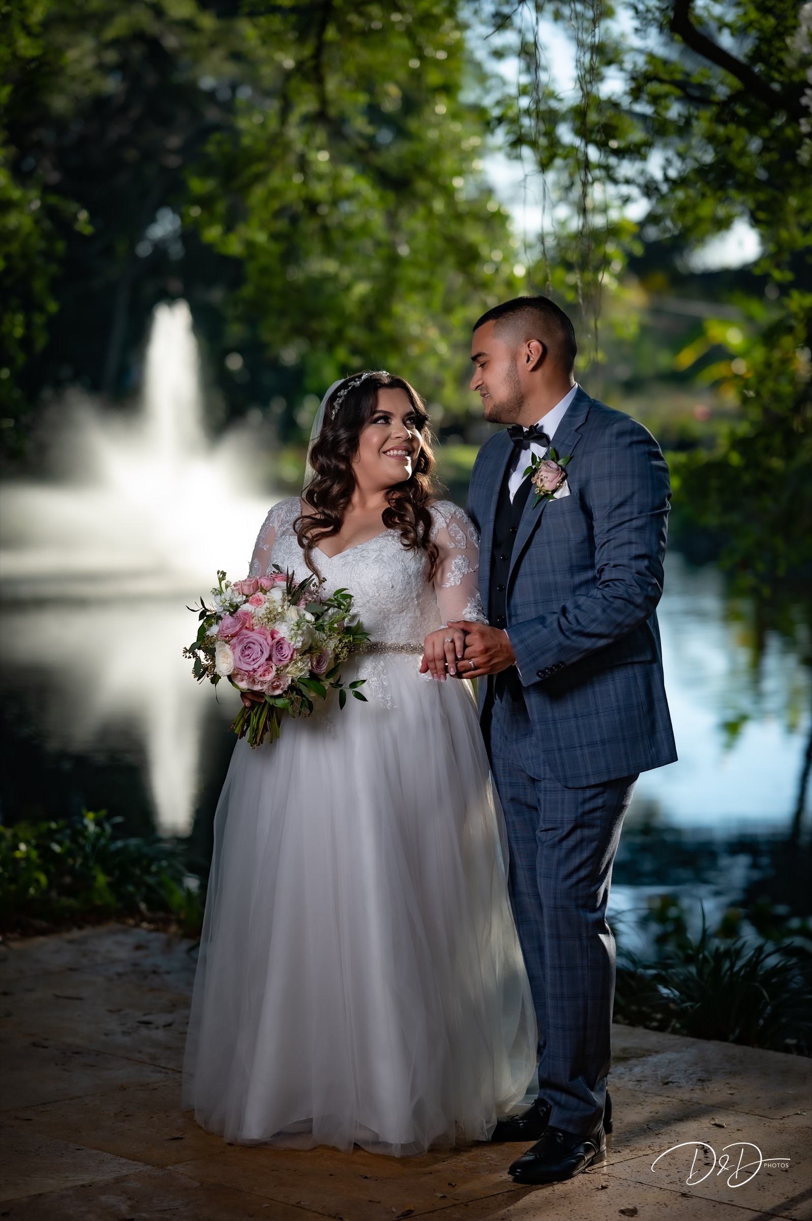 Newlyweds smiling together beside a South Florida garden fountain